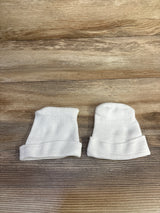 Top-down view of two white preemie fold-over baby hats showcasing fold-over cuffs on wood background
