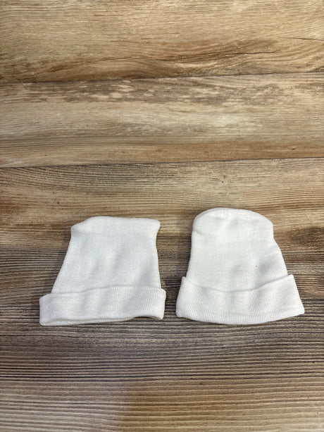 Top-down view of two white preemie fold-over baby hats showcasing fold-over cuffs on wood background