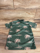 Back view of Hamakua Keiki green polo shirt (3T) showing pink palm tree print, short sleeves, and camp collar on wood floor
