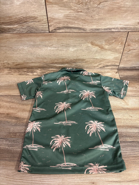 Back view of Hamakua Keiki green polo shirt (3T) showing pink palm tree print, short sleeves, and camp collar on wood floor