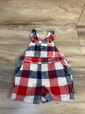 Front flat lay of Oshkosh shortalls 12M in red, navy and white plaid with adjustable metal buckle straps, bib pocket on wood floor