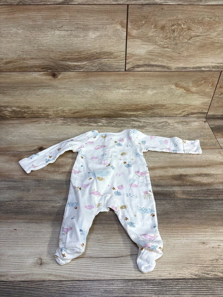 Flat lay of white footed baby sleeper with pastel ocean print showing whales, shells, and starfish, size 3M on wood background