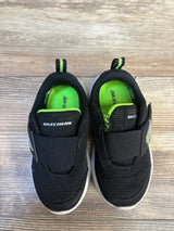 Black and green Skechers kids sneakers with Velcro straps on wood floor