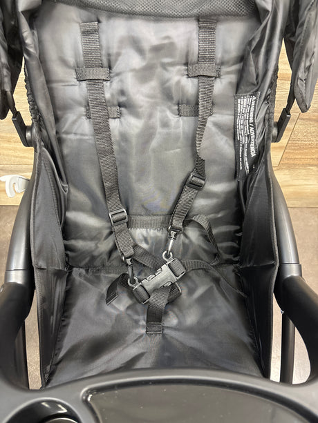 Close-up view of Kolcraft Cloud Premier Lightweight Stroller in Black showcasing five point harness with wood floor background
