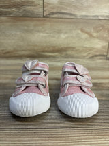 Pink toddler shoes with glitter heart straps and white rubber toes on wood floor