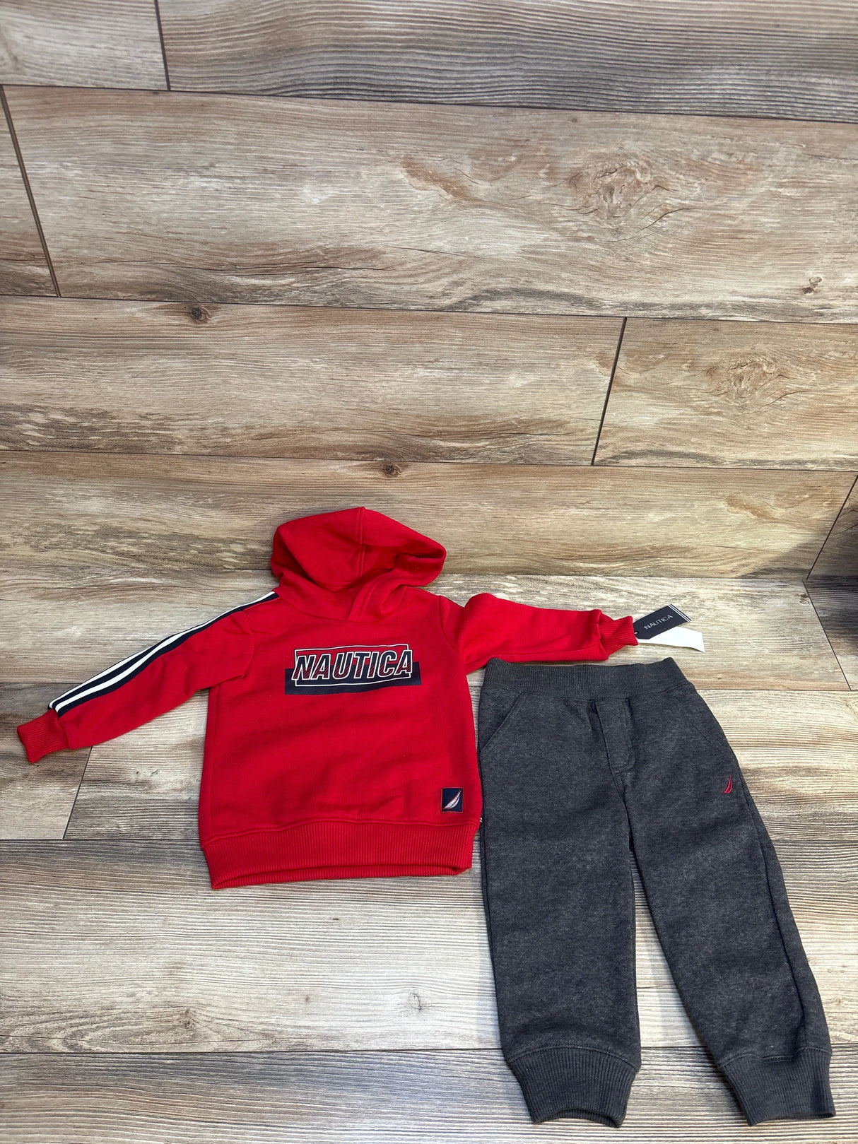 Red Nautica toddler hoodie with grey sweatpants, kids clothing set on wood floor