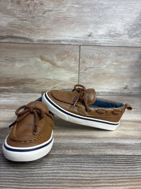 Brown toddler boat shoes with white soles and laces on wood background, kids resale store item