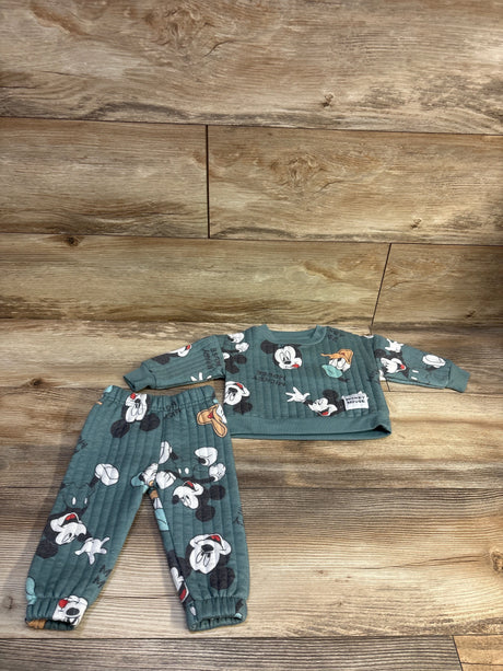 Top view of green Disney Baby 2-piece Mickey Mouse sweatshirt and joggers set with all-over character print on wood flooring