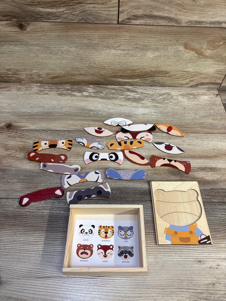 Top-down view of Animal Emotions wooden puzzle box showing 18 animal face pieces beside the wooden tray on a light wood surface