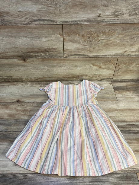 Flat lay of girls Oshkosh button-front dress with pastel vertical stripes, short puff sleeves, and gathered skirt on wood floor