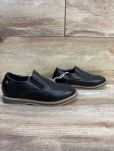 Black leather slip-on kids dress shoes with brown soles on wooden background
