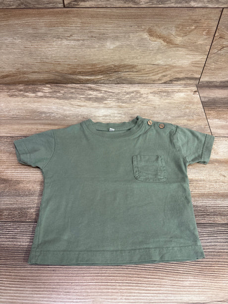Zeeman solid green short sleeve pocket shirt for babies size 3-6m on a wood background