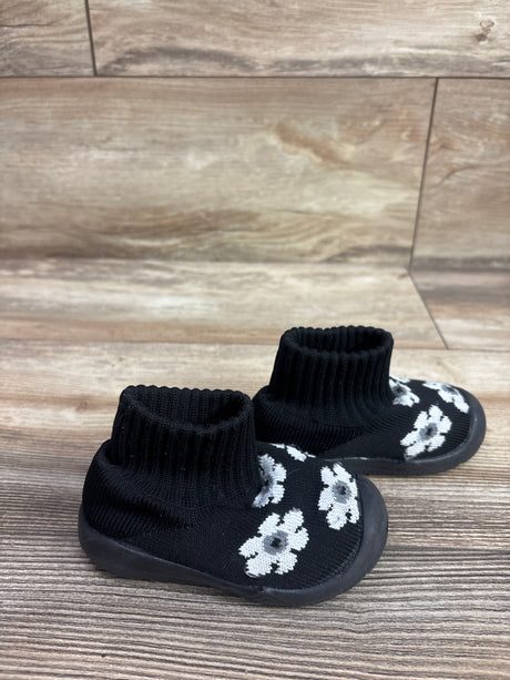 Angled view of black Morendl Floral Sock Shoes in size 4.5C showcasing ribbed knit ankle uppers and white floral motifs on a wood floor