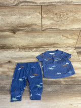 Flat lay of blue 2-piece dinosaur baby set: henley top with two buttons and matching elastic pants on wood background