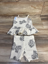 Flat lay of Carter's cream 2-piece ribbed tank and shorts set showing black butterfly print and ruffle hem on wood background