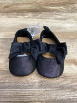 Pair of black baby shoes with large black bows on wooden surface, children's resale store item