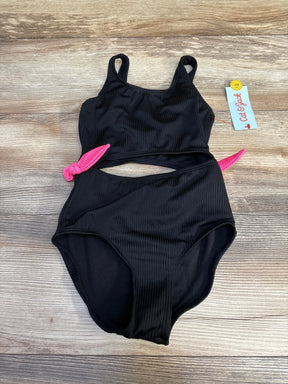 Top-down view of Cat & Jack black ribbed one-piece swimsuit with midriff cut-out and pink side ties on wood background