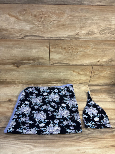 Top-down view of 2-piece floral swaddle and matching hat with lavender roses on black fabric, wood background