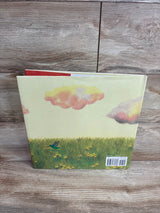 Back cover of a children's book with illustration of green grass, yellow flowers, a flying hummingbird, and pastel-colored clouds