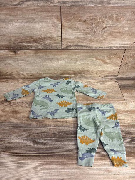Children's two-piece pajama set with colorful dinosaur prints on light gray fabric laid on wood floor