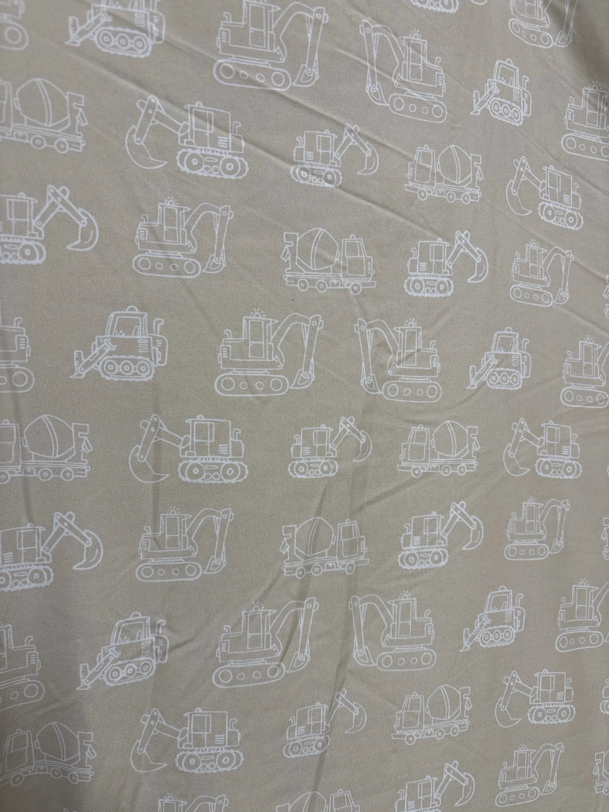 Top view of Tiny Adventures round baby playmat showing reversible tan fabric with white construction vehicle print, 36 x 36 in