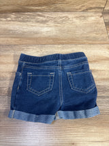 Back view of Jumping Beans pull-on blue denim toddler shorts size 18m showing elastic waistband, cuffed hems, and back pockets on wood surface