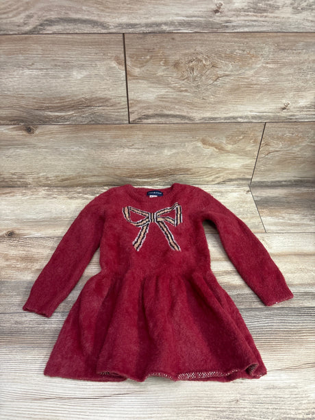 Front view of Andy & Evan fuzzy eyelash knit long sleeve sweater dress in red, showcasing bow detail with wood plank background