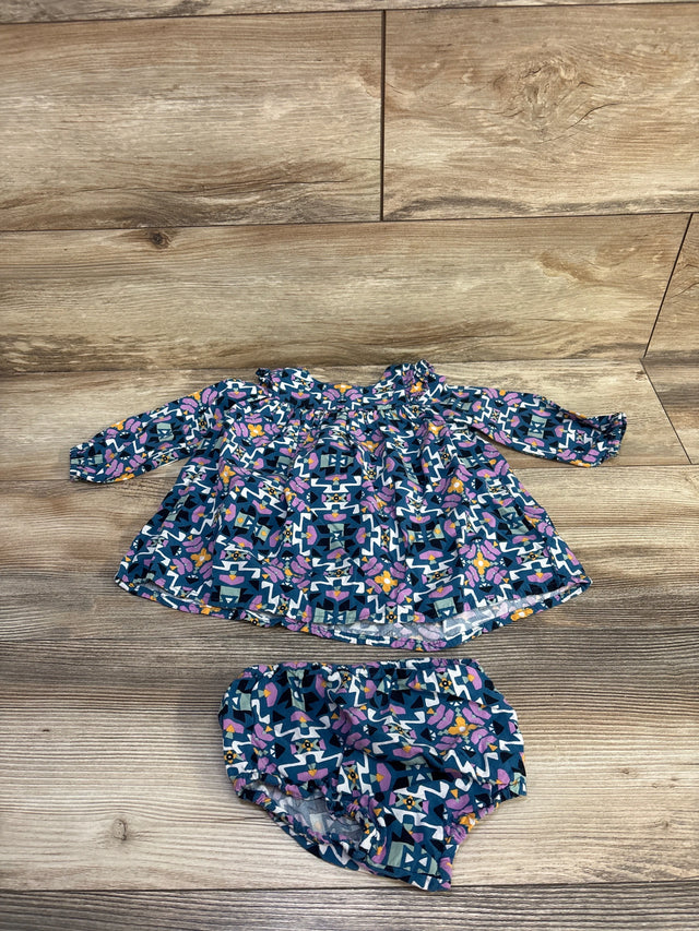 Flat-lay of girls Wrangler long-sleeve dress and matching bloomers (size 6-9 months) showing navy geometric and floral print, ruffle collar, and elastic waist on wood background