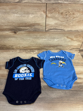 Two Los Angeles Chargers baby onesies, one navy and one blue, on a wood background
