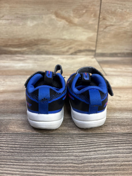 Rear view of Nike Cosmic Runner TD size 5C sneakers showcasing Black Hyper Royal uppers, white soles, and a wood floor