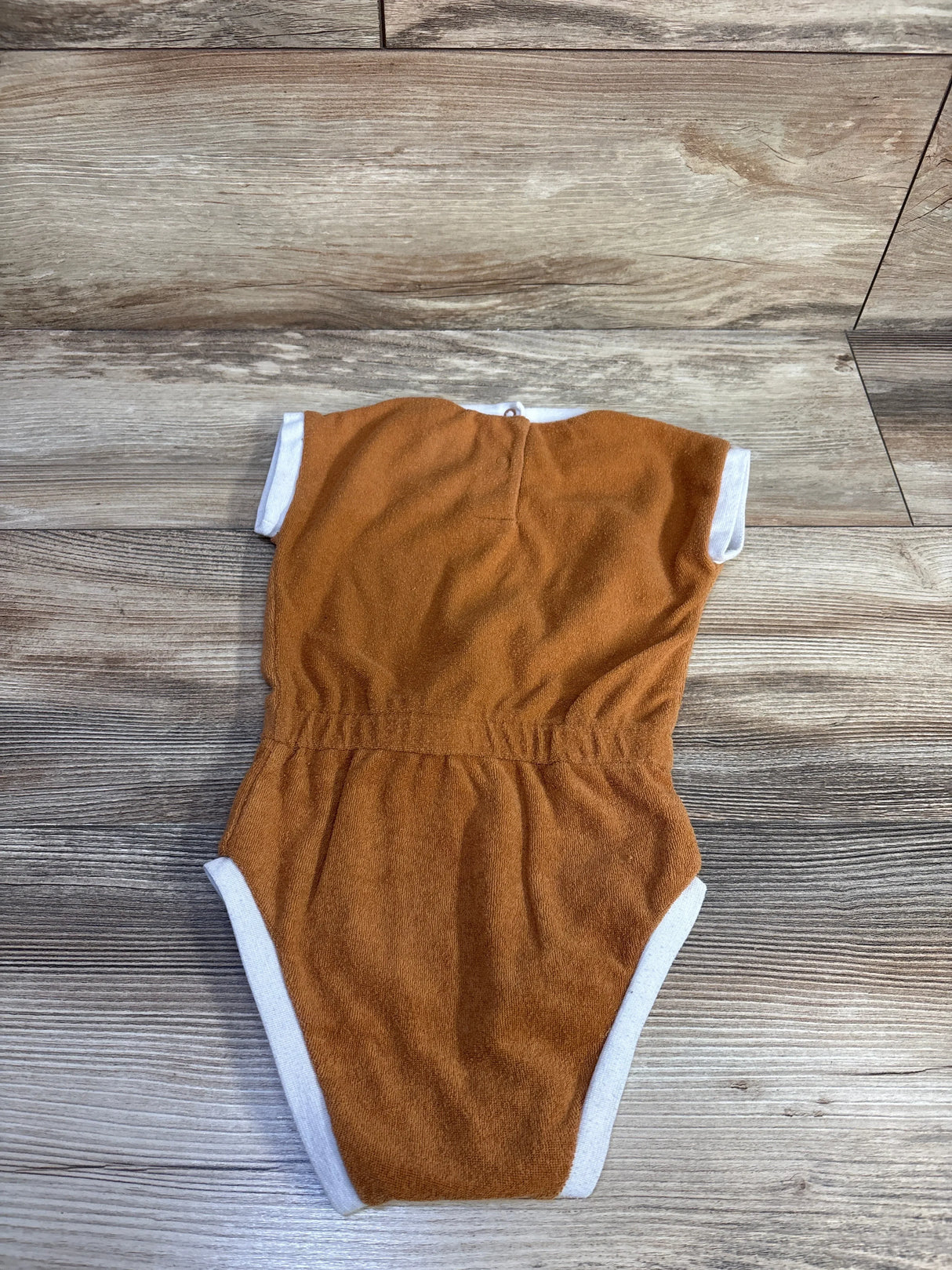 Back flat lay of Lila and Jack terry cloth bodysuit, brown with white trim and elastic waist on wood background