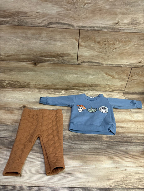 Flat lay of a Disney Baby Toy Story sweatshirt and pants set with embroidered character faces, blue sweatshirt, and brown quilted pants