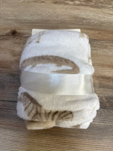 Soft white baby blanket with brown cat print, tied with ribbon, perfect for nursery or baby shower gifts.