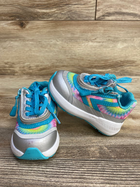 Pair of kids' athletic shoes with blue laces and colorful tie-dye pattern on a wood floor
