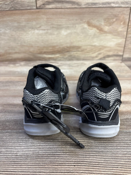 Rear view of Athletic Works two-strap black sneakers size 8C showing silver heel, white sole and tag on wood floor