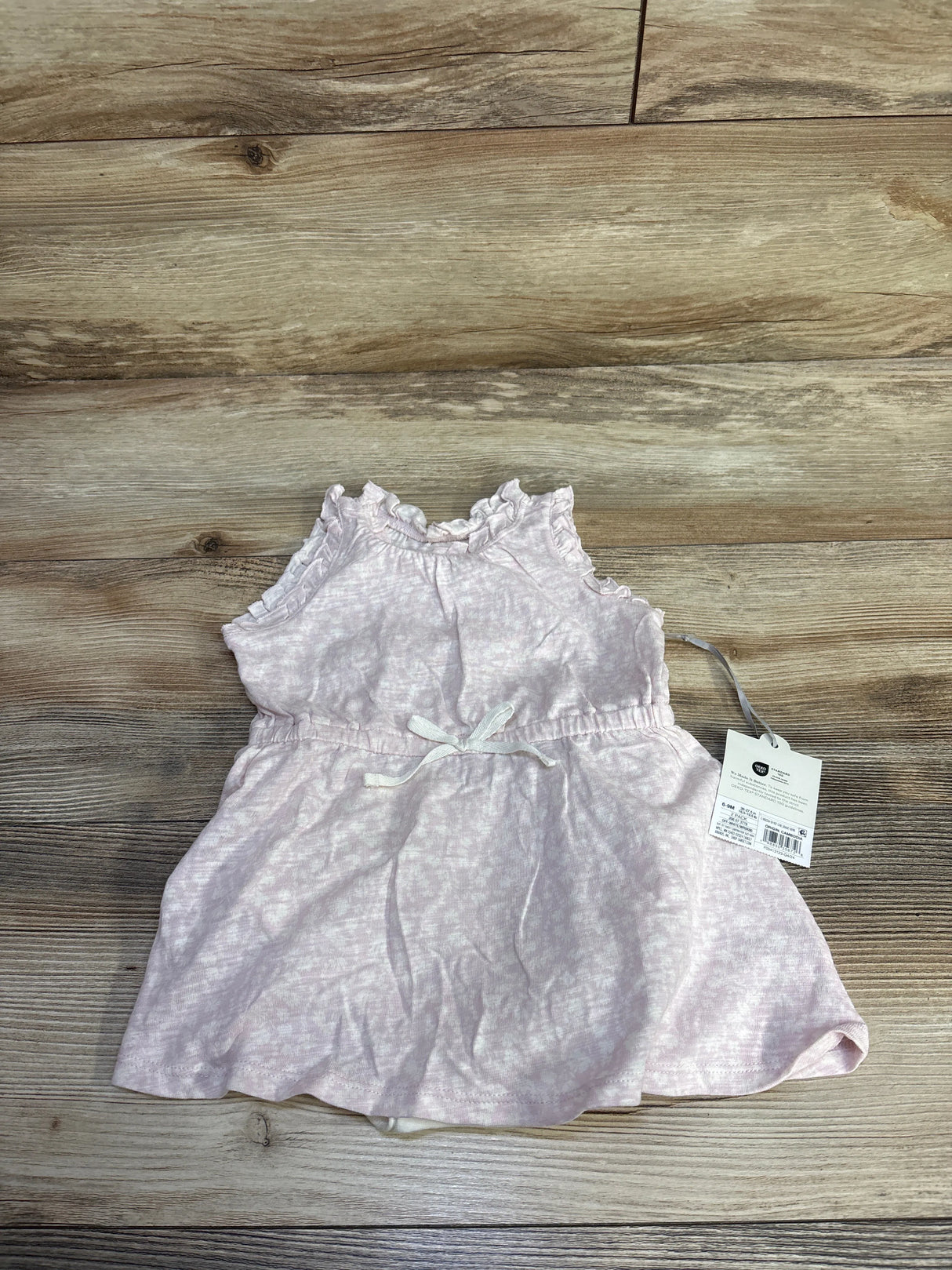 Top-down view of Cloud Island pink 2-piece baby tank dress with matching bloomers, ruffled shoulders and waist bow on light wood background