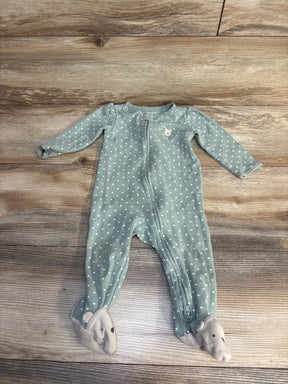 Green baby onesie with white hearts and bear feet, laid on wood floor