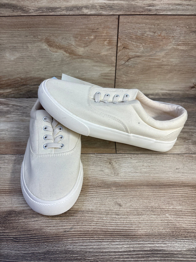 Three-quarter view of Cat & Jack Tyler slip-on sneakers with off-white canvas upper and white rubber sole on wood background