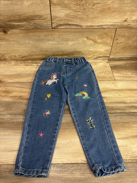 Front view of Shein blue embroidered jeans in size 4T showcasing unicorn, rainbow, floral, heart, and star designs on a wood floor