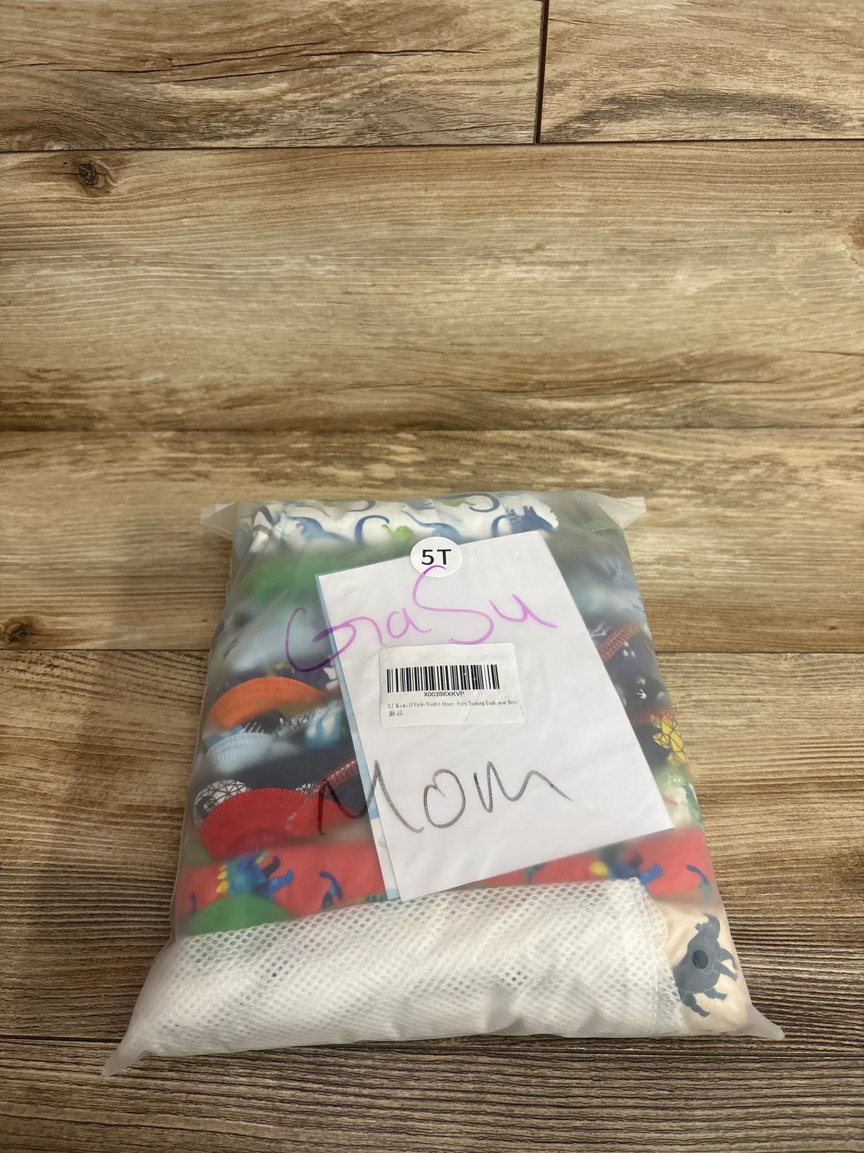 Top view of 10-pack potty training underwear, size 5T, double absorbency, in a clear bag showing colorful prints on a wood background
