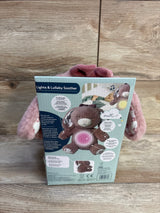 Back of NEW DreamGro Lights and Lullaby Soother pink bunny plush in original retail packaging with instructions and brown bear graphic on wood plank floor