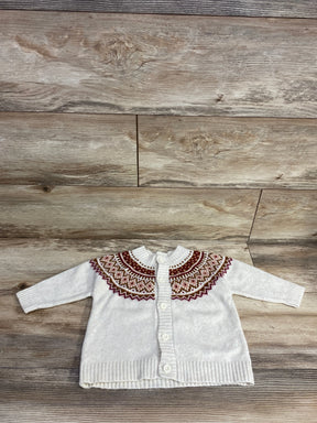 White baby cardigan with colorful patterned yoke and buttons, laid flat on wood floor