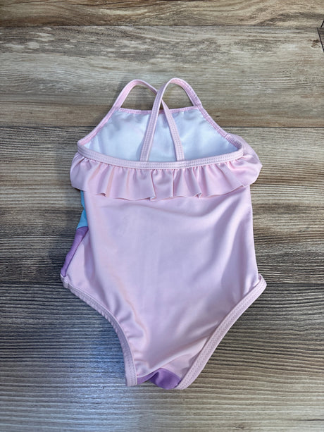 Light pink toddler swimsuit with ruffle trim and double straps on wood background