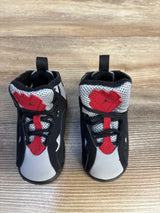 Top down view of Air Jordan True Flight TD sneakers in black grey and red with Jumpman logo on tongue and hook and loop strap on wood plank floor