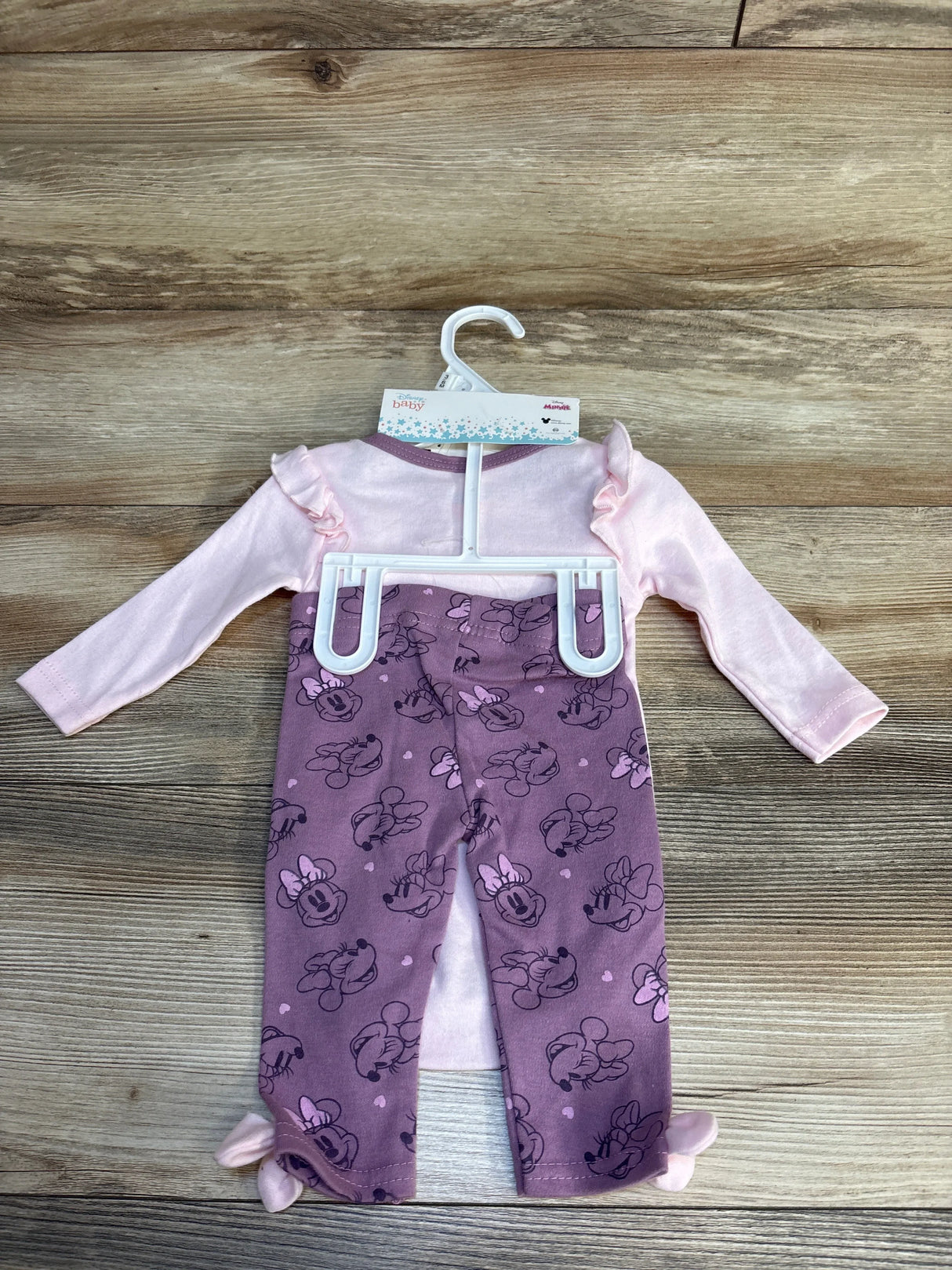 Pink Minnie Mouse baby outfit with ruffled top and purple printed pants on hanger