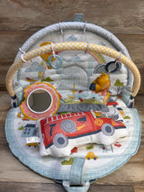 Top view of Yookidoo 3-in-1 Urban Gymotion Lay to Sit-Up Play Mat with arches, mirror, and hanging toys on a wood floor