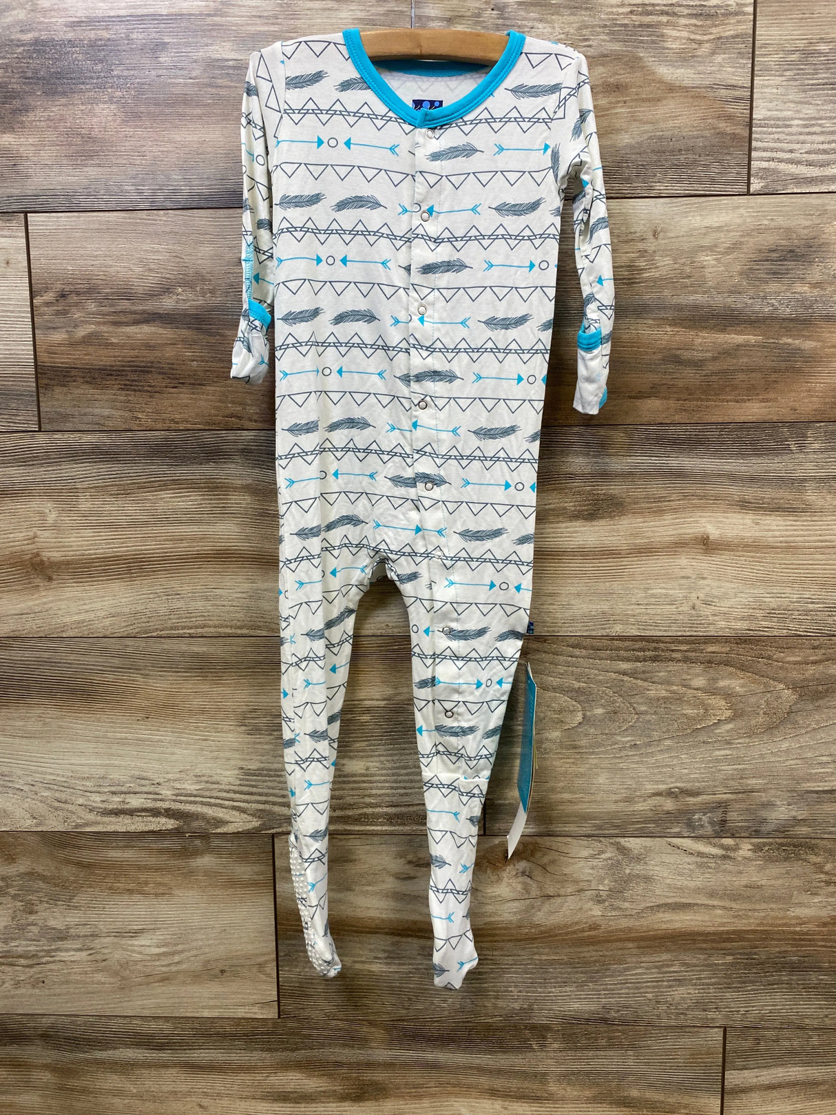 Baby sleeper with tribal arrow and feather pattern, blue trim, long sleeves, wood background
