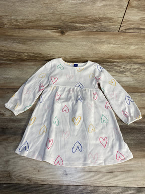 White long sleeve toddler dress with colorful heart print on wood background