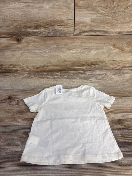 Back view of Baby Gap ivory short-sleeve baby shirt showing plain back and neck size tag on wood floor background