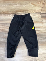 Flat lay of toddler Nike joggers, black with volt Swoosh, elastic waistband and ribbed ankle cuffs on wood floor, size 2T